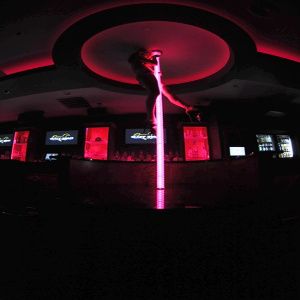 image of a stripper at the top of a neon pink stripper pole in club highkighted with neon lighting for a beat titled surreal